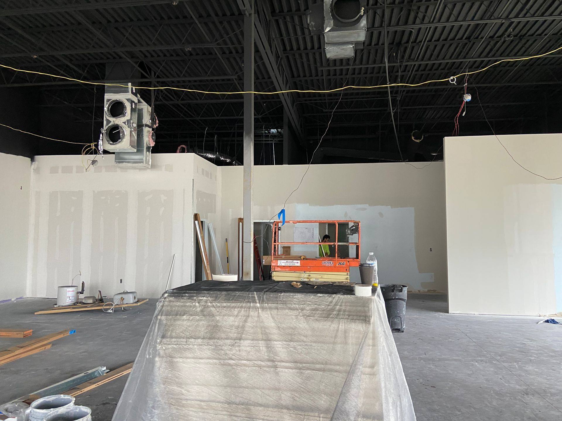 Progress: the new partition walls taped and floated, ductwork run and the roof deck painted out, during the Kung Fu Academy of North Texas remodel in McKinney, TX