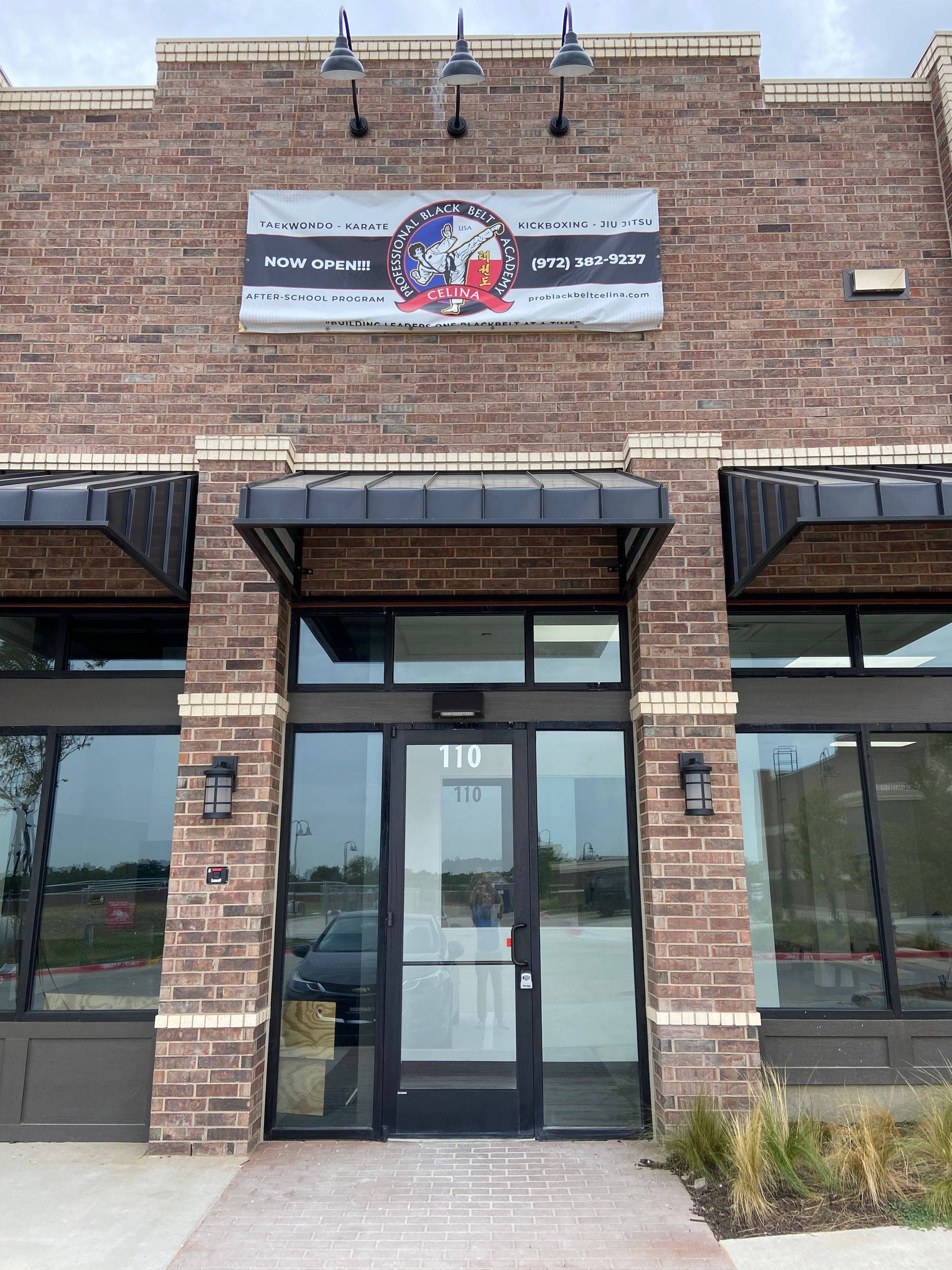 The finished storefront of Professional Black Belt Academy in Celina, TX, with the “Now Open” banner above the entry