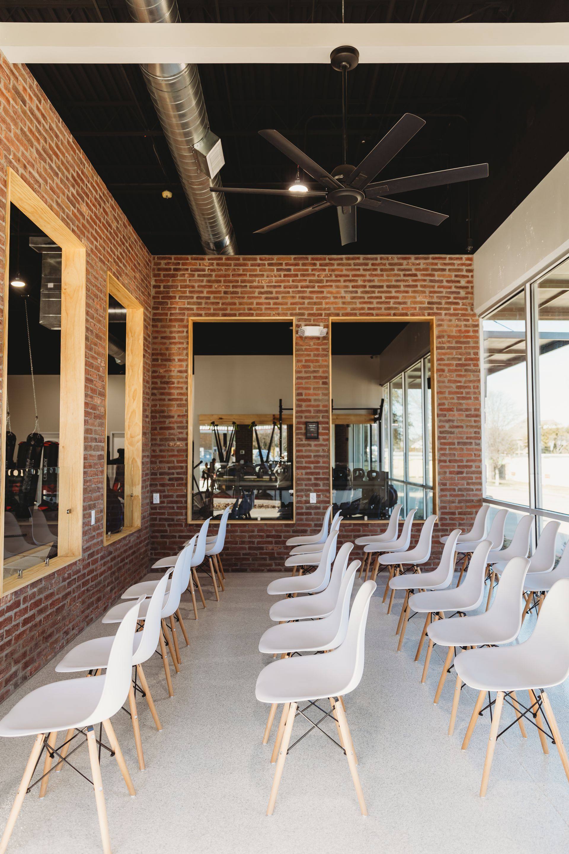 After: the finished spectator seating against the brick wall, looking through the viewing windows onto the training floor at Kung Fu Academy of North Texas in McKinney, TX